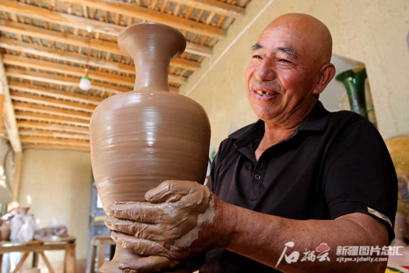 6月19日，英吉沙縣芒辛鎮(zhèn)恰克日庫(kù)依村土陶非遺傳承人阿卜杜熱合曼·麥麥提敏在欣賞剛制作的土陶作品。石榴云/新疆日?qǐng)?bào)記者 蔡增樂(lè) 攝