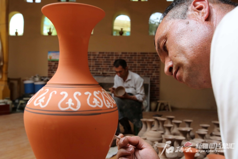 6月19日，恰克日庫(kù)依村土陶制作藝人伊馬木·艾力在土陶罐上畫(huà)畫(huà)。石榴云/新疆日?qǐng)?bào)記者 蔡增樂(lè) 攝