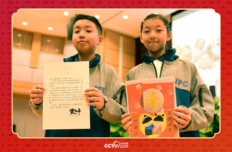 圖為香港“少年警訊”成員郭宏晞（左）展示習主席回信、羅顥凝（右）展示送給習主席的賀卡并合影。